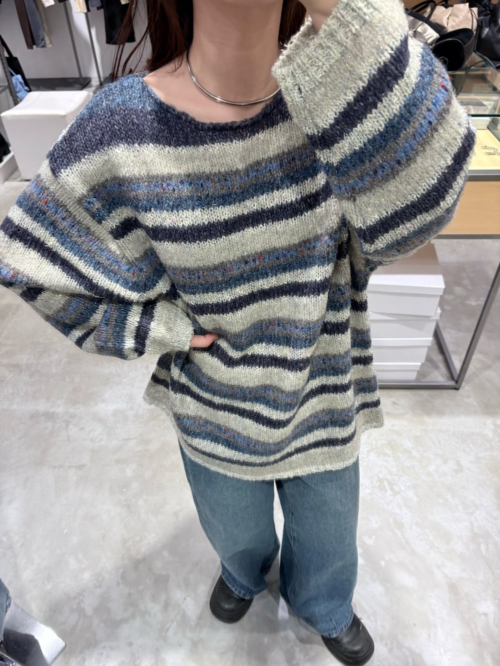 ブルー系のニット/セーター、ブルー系のデニムパンツ、ブラック系のショルダーバッグを着用したレディースの秋コーディネートの5枚目の写真