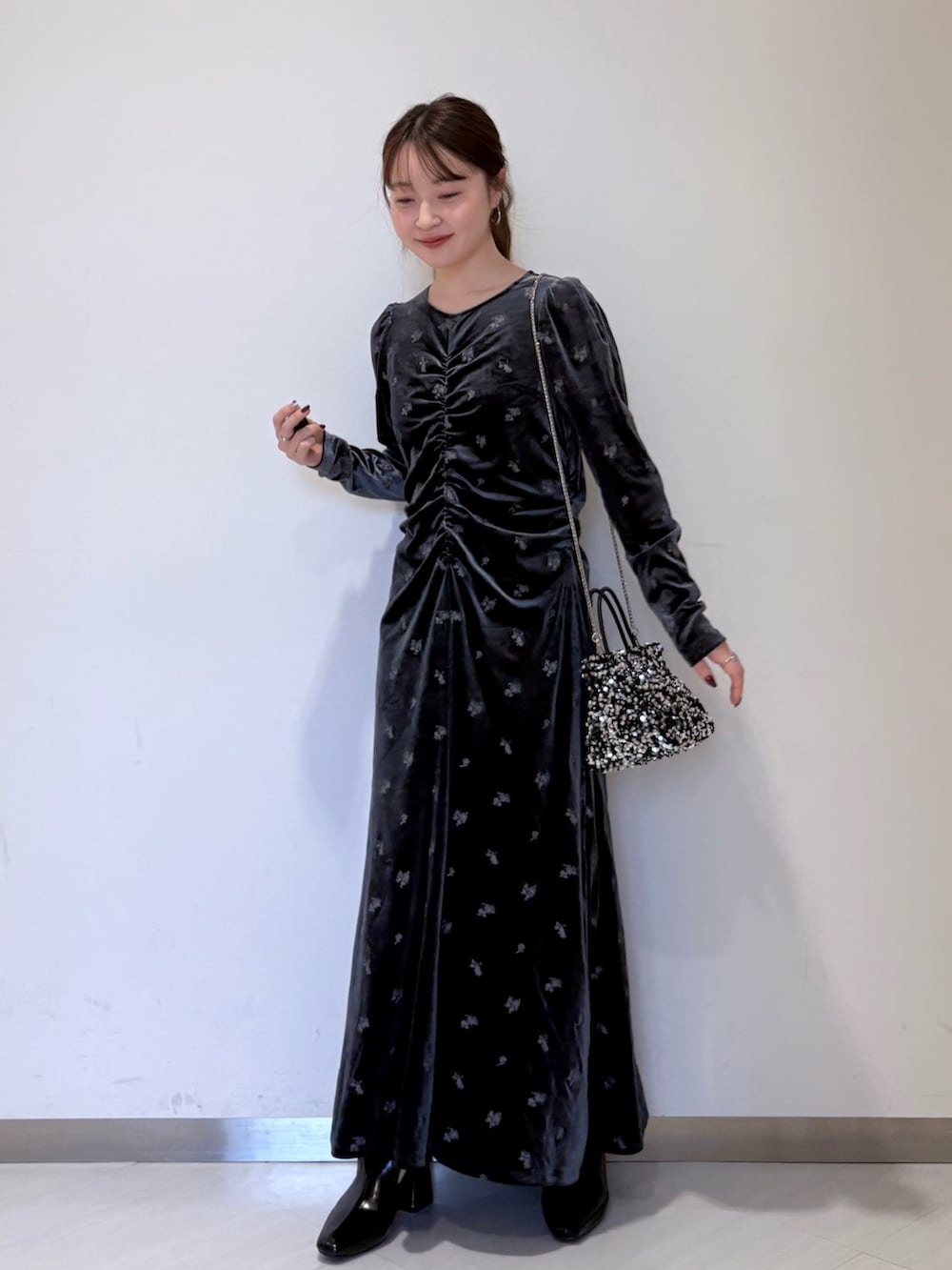 グレー系のワンピース、ブラック系のステンカラーコート、ブラック系のパンプスを着用したレディースの冬コーディネートの2枚目の写真