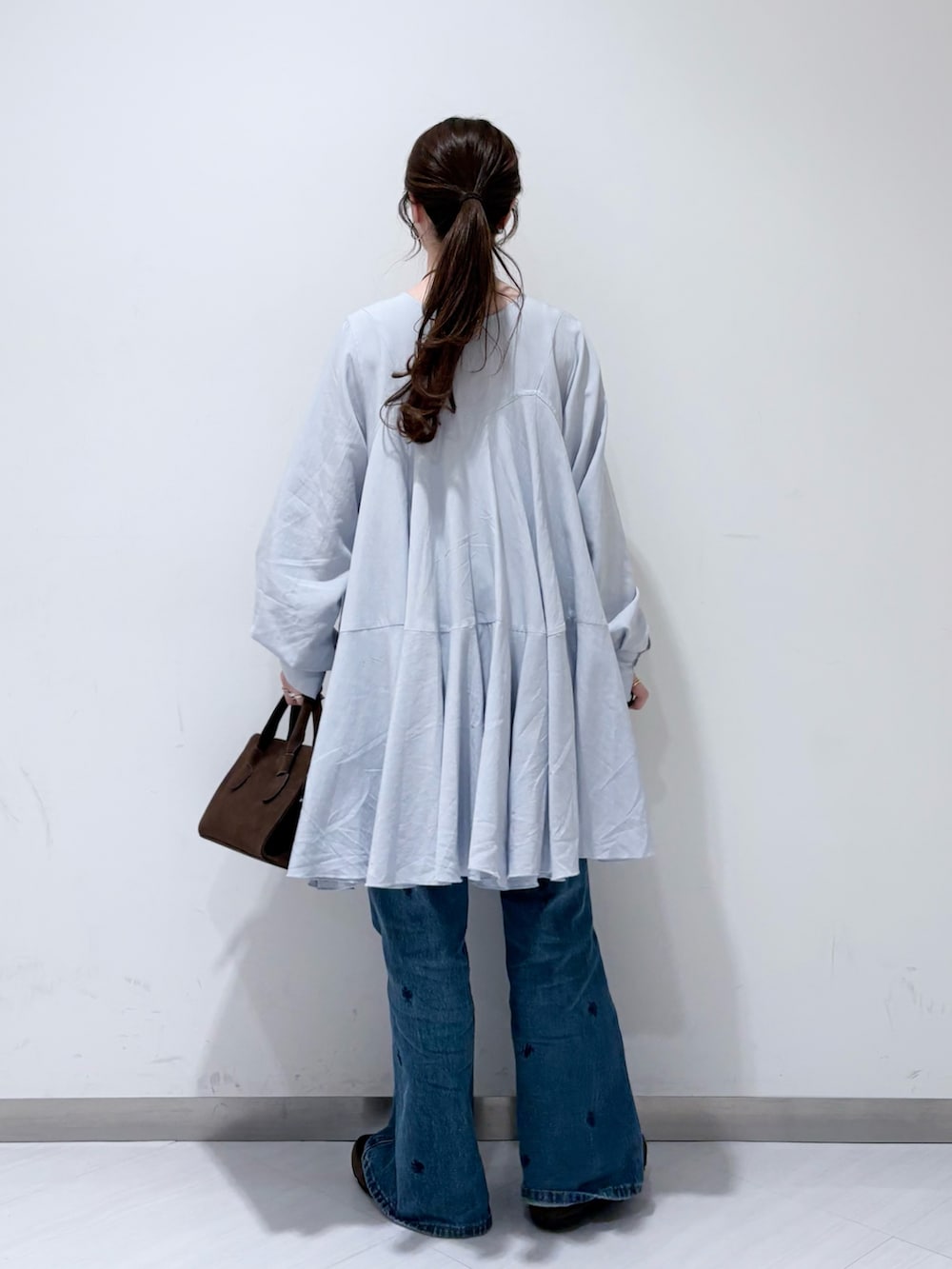 ブルー系のワンピース、ブラウン系のボストンバッグ、ブルー系のデニムパンツを着用したレディースの冬コーディネートの2枚目の写真