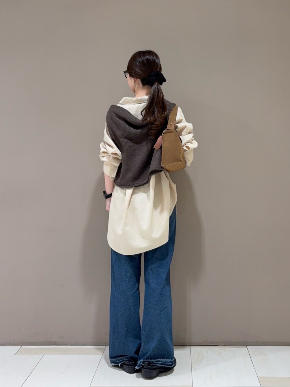 ブルー系のデニムパンツ、ベージュ系のシャツ/ブラウス、ブラウン系のニット/セーターを着用したレディースの秋コーディネートの4枚目の写真