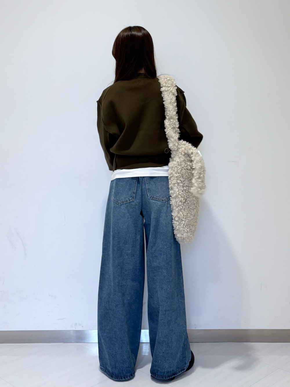 グリーン系のニット/セーター、ホワイト系のTシャツ/カットソー、ブルー系のデニムパンツを着用したレディースの秋コーディネートの3枚目の写真