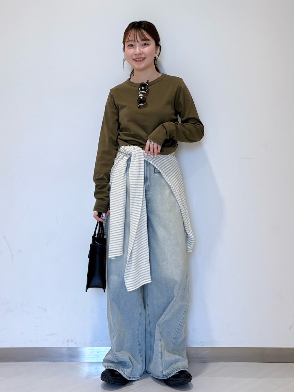 グリーン系のTシャツ/カットソー、ホワイト系のニット/セーター、ブラック系のハンドバッグを着用したレディースの春コーディネートの4枚目の写真