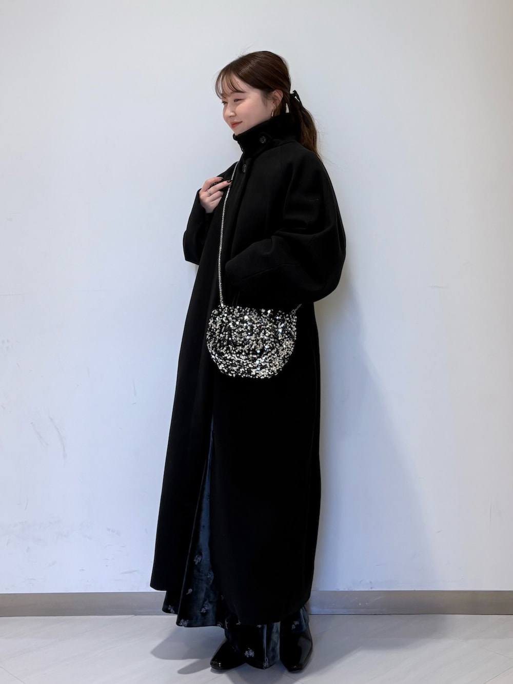 グレー系のワンピース、ブラック系のステンカラーコート、ブラック系のパンプスを着用したレディースの冬コーディネートの5枚目の写真