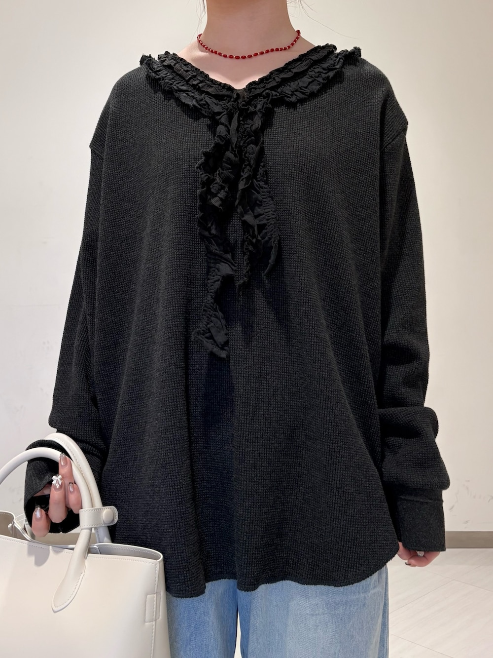 ブラック系のパンプス、ホワイト系のハンドバッグ、ブルー系のデニムパンツを着用したレディースの春コーディネートの5枚目の写真