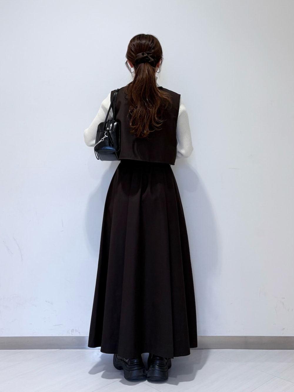 ブラック系のショルダーバッグ、ブラウン系のワンピース、ホワイト系のニット/セーターを着用したレディースの冬コーディネートの3枚目の写真