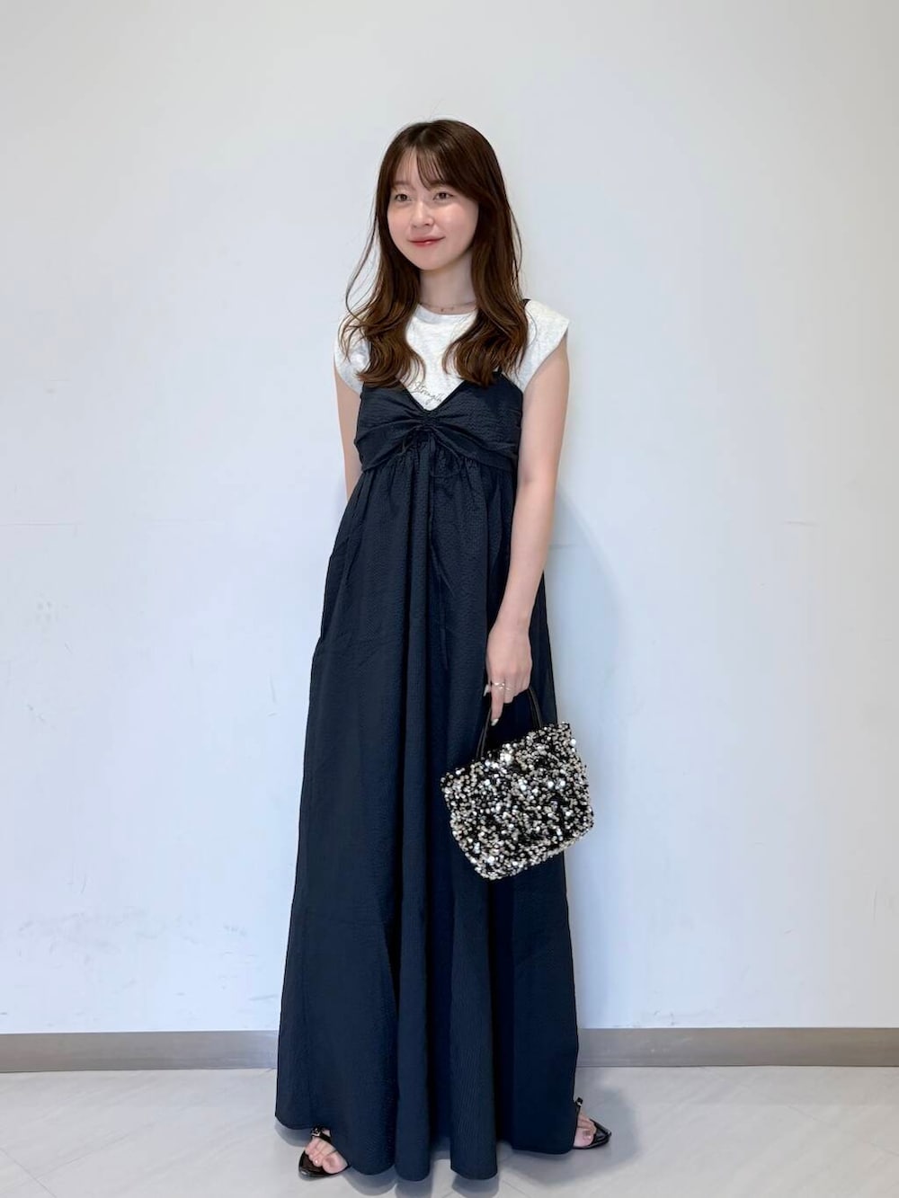 シルバー系のショルダーバッグ、ブルー系のワンピース、ベージュ系のTシャツ/カットソーを着用したレディースの夏コーディネートの2枚目の写真