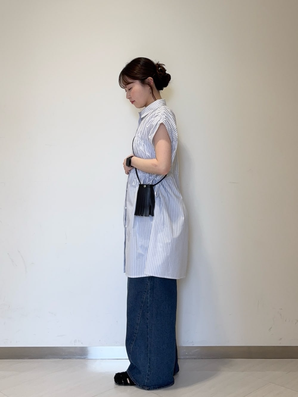ホワイト系のワンピース、ブルー系のデニムパンツ、ブラック系のサンダルを着用したレディースの夏コーディネートの2枚目の写真