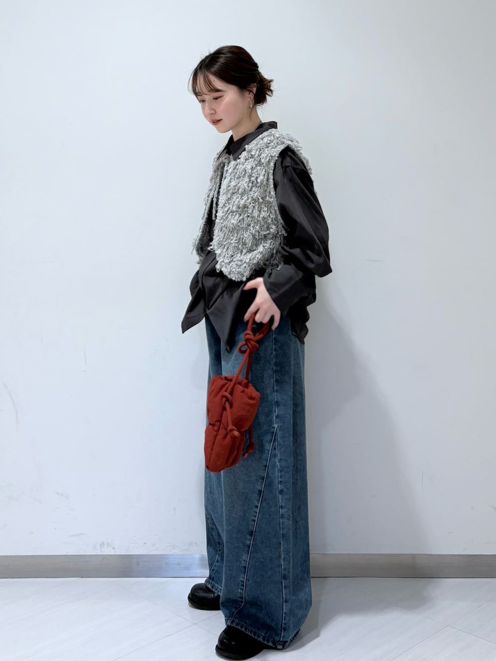 グレー系のベスト、グレー系のシャツ/ブラウス、ブルー系のデニムパンツを着用したレディースの秋コーディネートの2枚目の写真