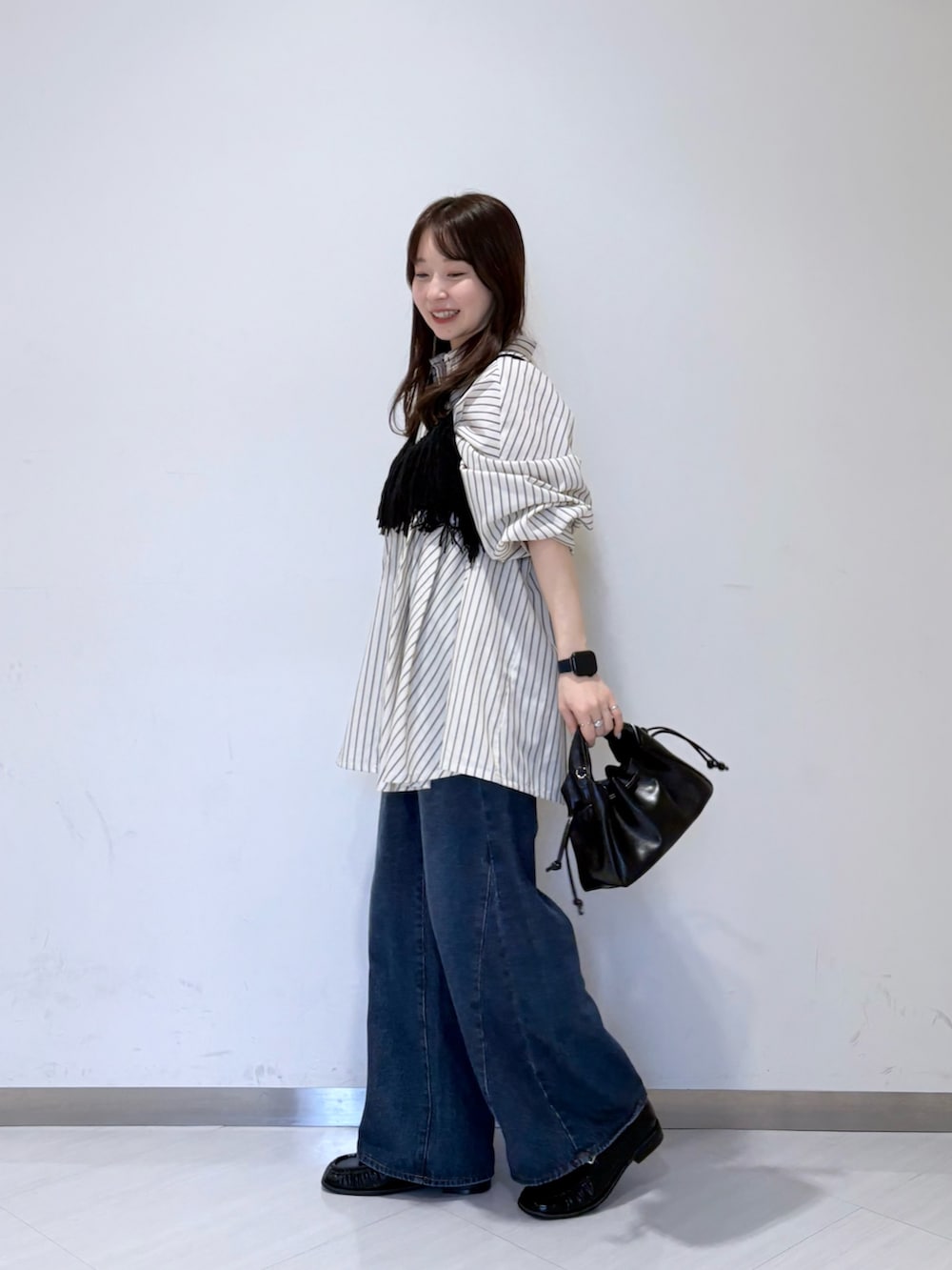 ブラック系のニット/セーター、ブルー系のデニムパンツ、ブラック系のハンドバッグを着用したレディースの夏コーディネートの2枚目の写真