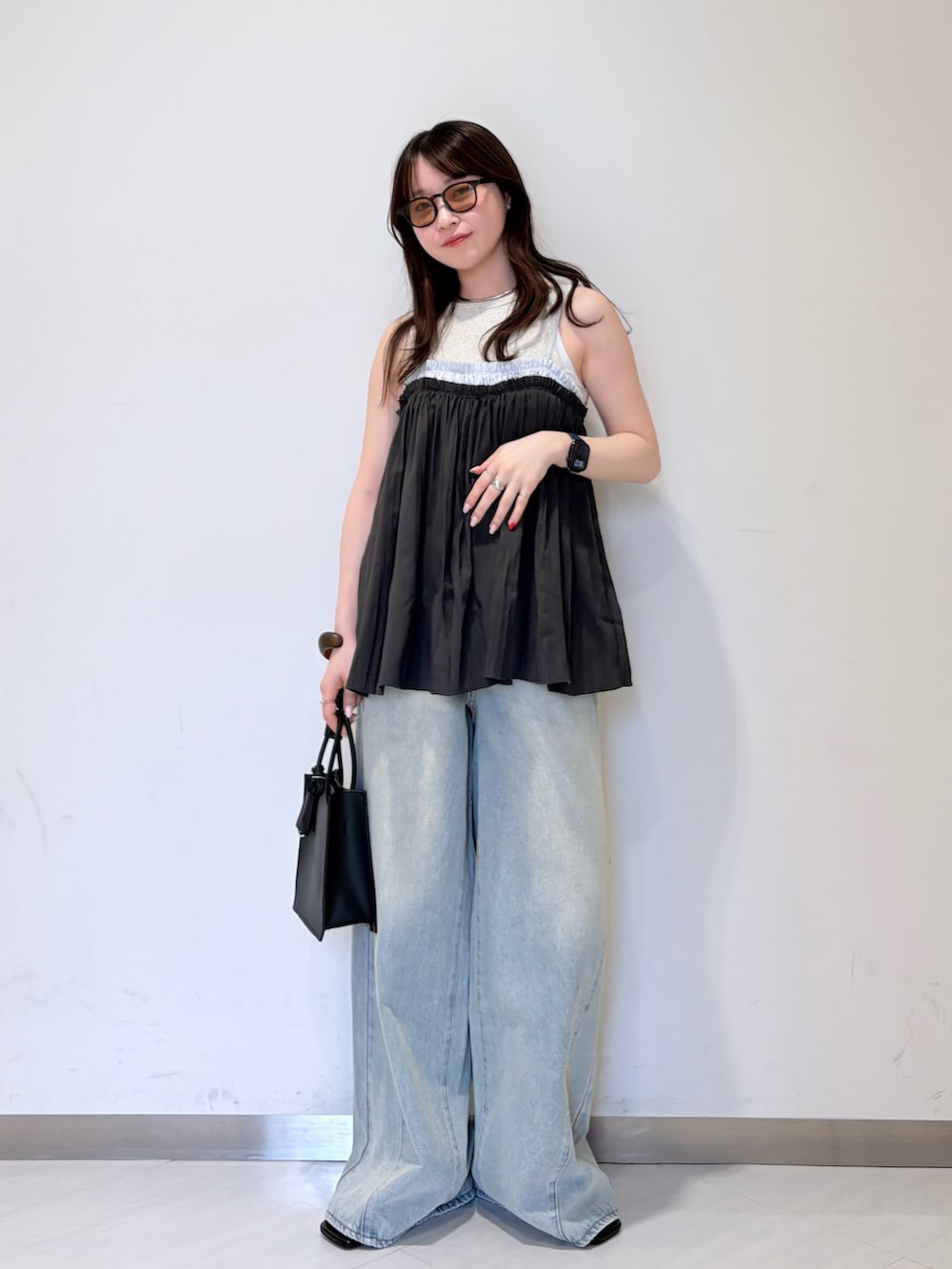 ブラック系のサンダル、ホワイト系のハンドバッグ、ブルー系のデニムパンツを着用したレディースの春コーディネートの4枚目の写真