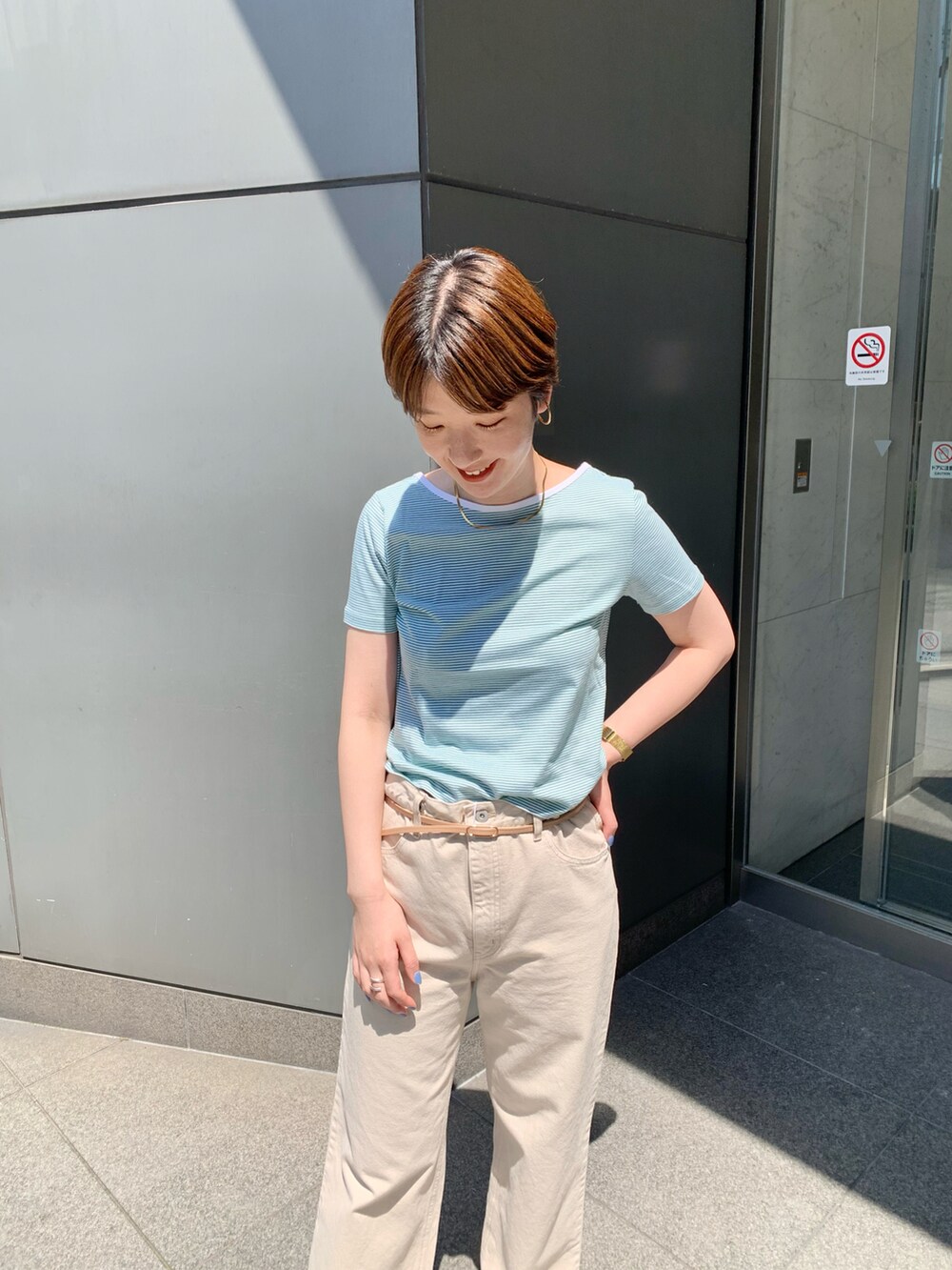 グリーン系のTシャツ/カットソー、ベージュ系のデニムパンツ、ブラック系のサンダルを着用したレディースの春コーディネートの2枚目の写真