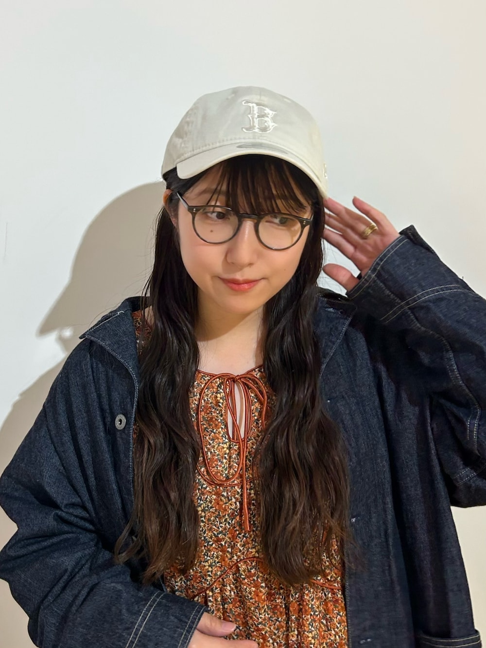 オレンジ系のワンピース、ベージュ系のキャップを着用したレディースの秋コーディネートの2枚目の写真