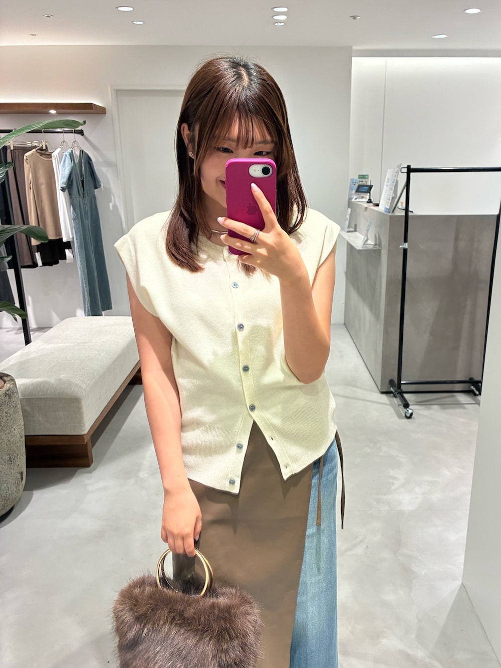 ホワイト系のニット/セーター、ブラウン系のスカート、ブルー系のデニムパンツを着用したレディースの夏コーディネートの2枚目の写真