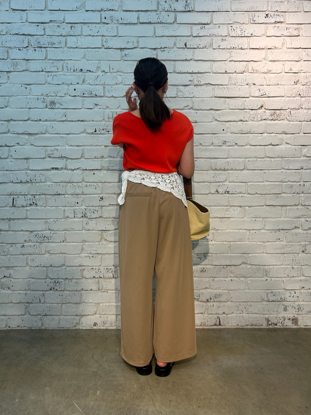 ベージュ系のその他パンツ、オレンジ系のニット/セーター、ベージュ系のハンドバッグを着用したレディースの夏コーディネートの6枚目の写真