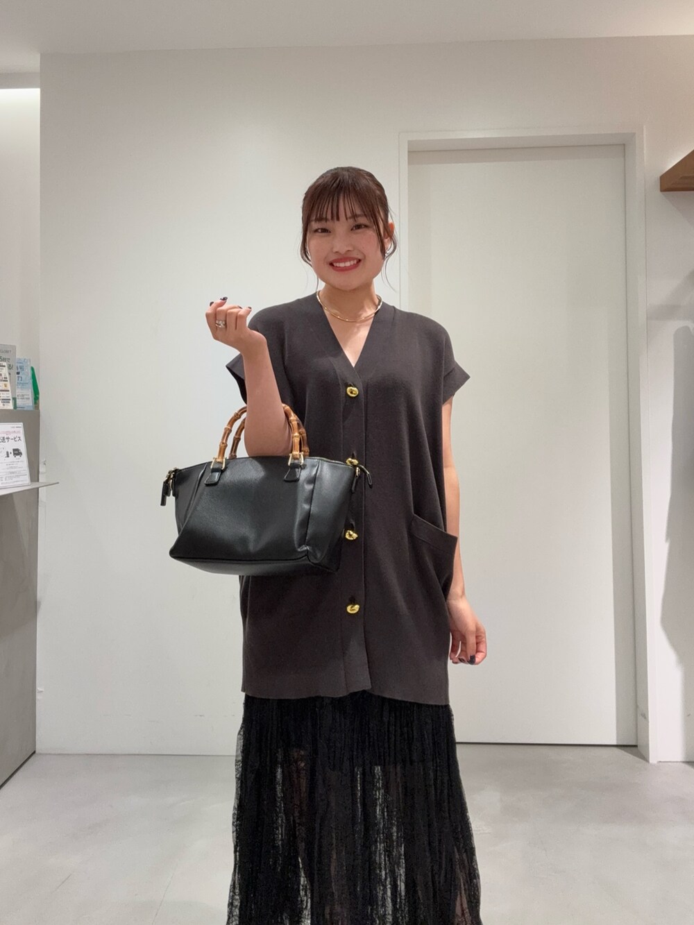 ブラウン系のカーディガン/ボレロ、ブラック系のスカート、ブラック系のバッグを着用したレディースの夏コーディネートの3枚目の写真