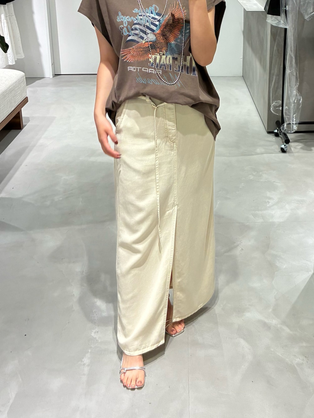 ベージュ系のスカート、ブラウン系のTシャツ/カットソーを着用したレディースの夏コーディネートの2枚目の写真