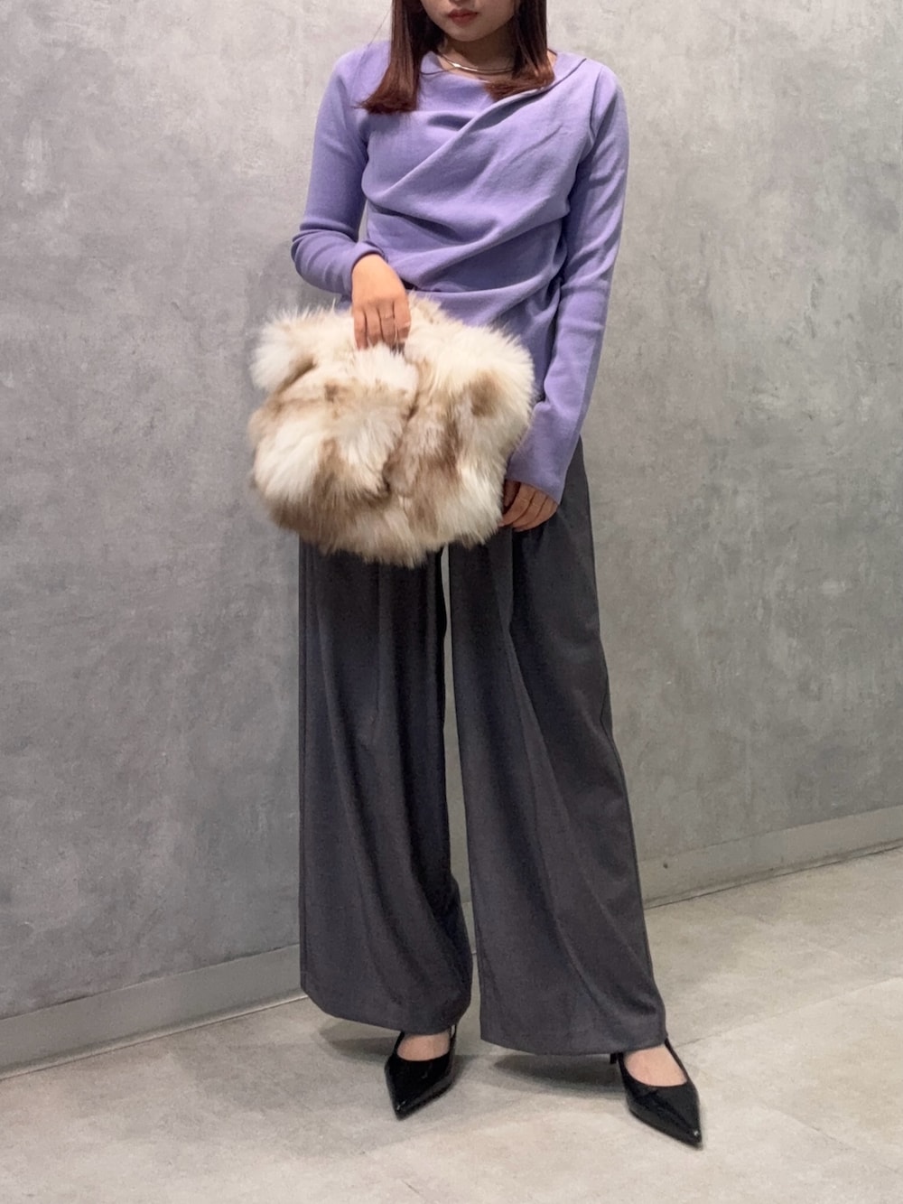 パープル系のニット/セーター、ホワイト系のクラッチバッグ、グレー系のその他パンツを着用したレディースの秋コーディネートの2枚目の写真
