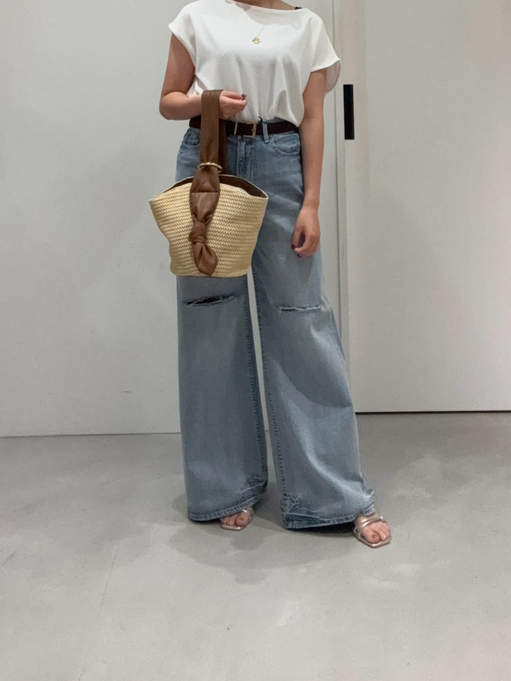 ブルー系のデニムパンツ、ホワイト系のシャツ/ブラウス、ベージュ系のハンドバッグを着用したレディースの夏コーディネートの2枚目の写真