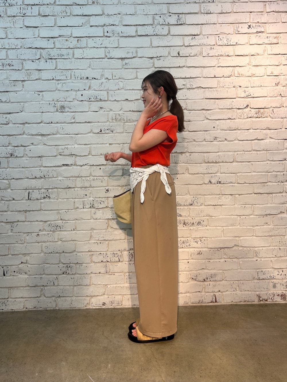 ベージュ系のその他パンツ、オレンジ系のニット/セーター、ベージュ系のハンドバッグを着用したレディースの夏コーディネートの4枚目の写真