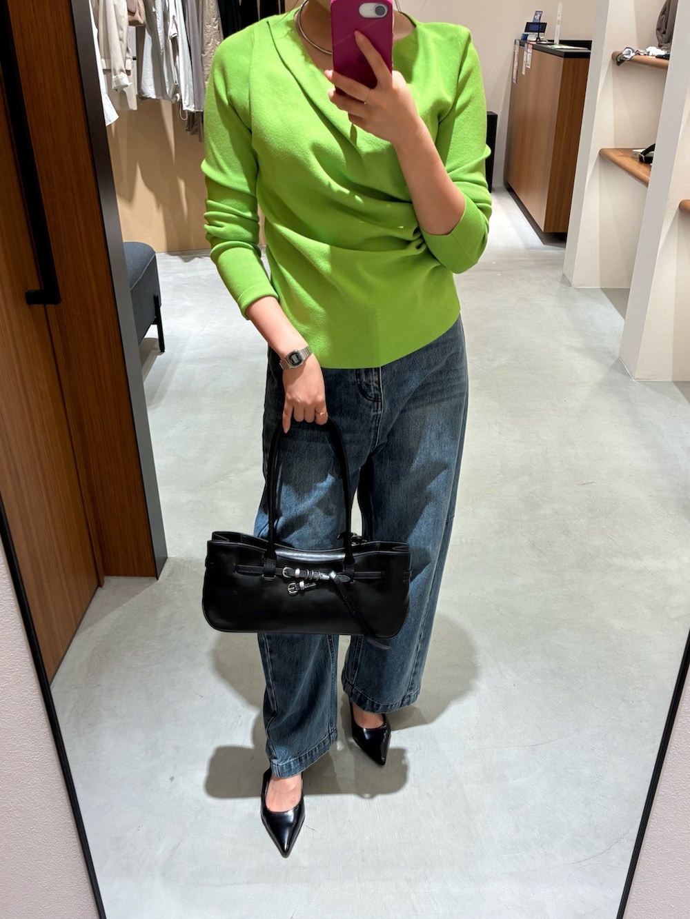 グリーン系のニット/セーター、ブルー系のデニムパンツ、ブラック系のパンプスを着用したレディースの秋コーディネートの2枚目の写真