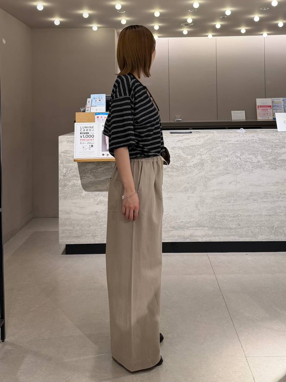 ベージュ系のデニムパンツ、ブラック系のローファー、ブラウン系のボディバッグ/ウエストポーチを着用したレディースの春コーディネートの2枚目の写真