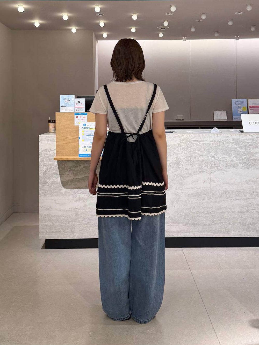ブルー系のデニムパンツ、ブラック系のサンダル、ホワイト系のTシャツ/カットソーを着用したレディースの夏コーディネートの2枚目の写真