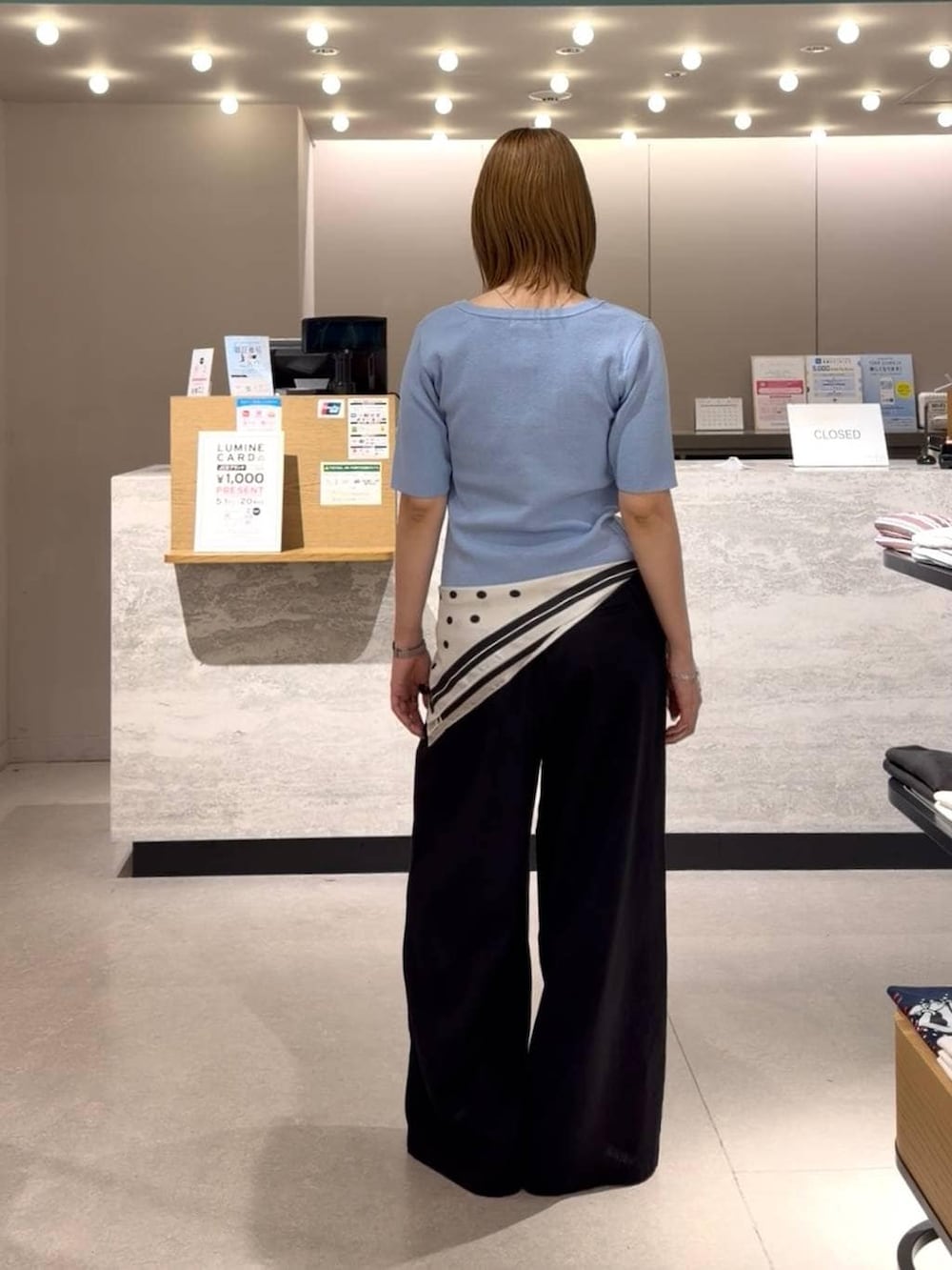 ブラック系のスラックス、ブラック系のローファー、ブルー系のカーディガン/ボレロを着用したレディースの春コーディネートの2枚目の写真