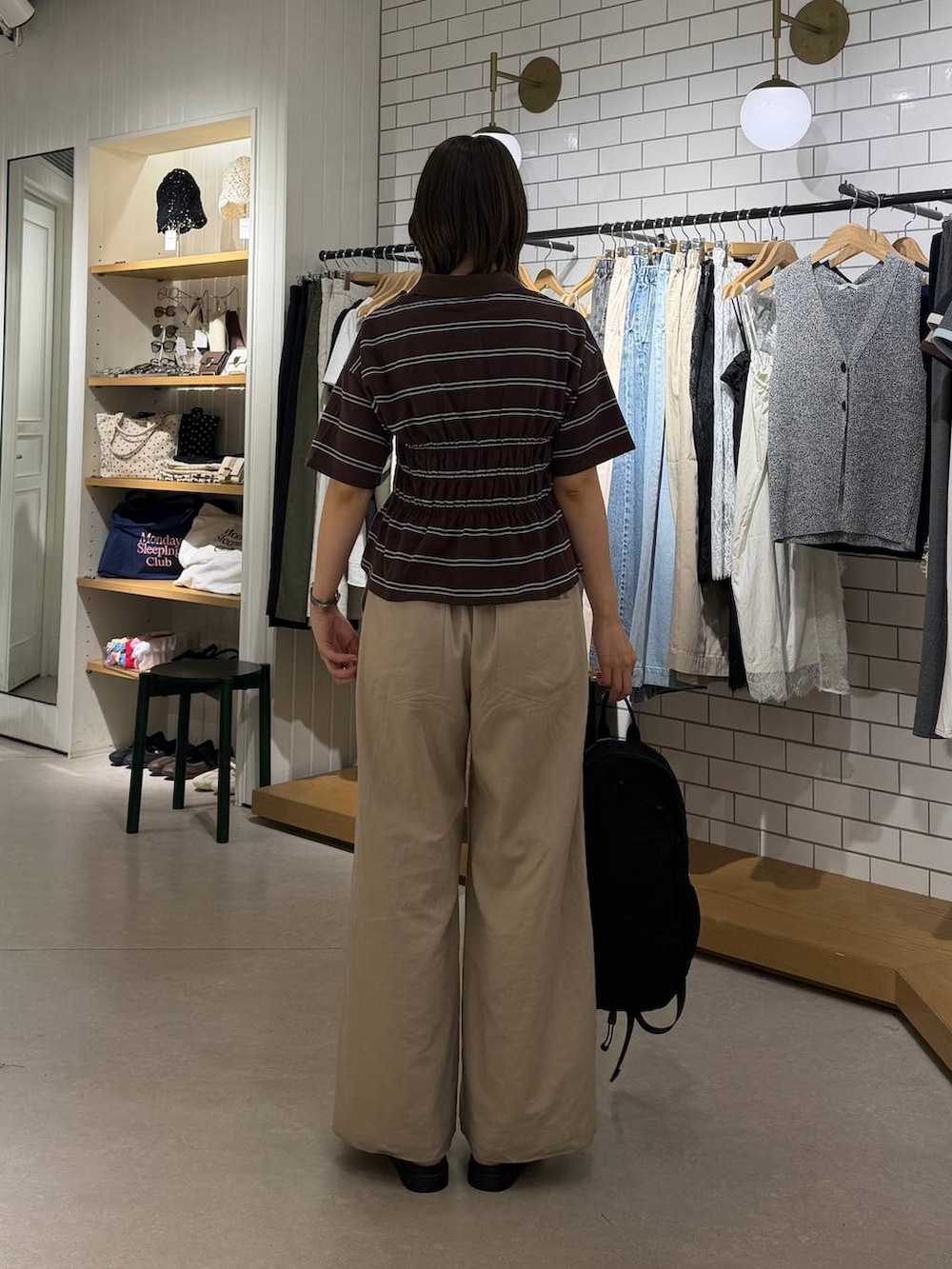 ベージュ系のデニムパンツ、ブラウン系のサンダル、ブラック系のバックパック/リュックを着用したレディースの春コーディネートの3枚目の写真