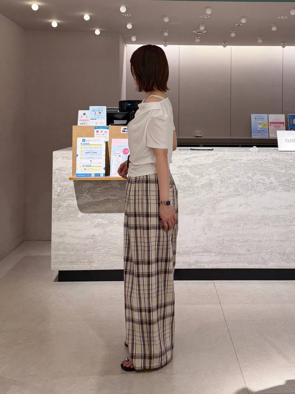 ホワイト系のTシャツ/カットソー、ベージュ系のスラックス、ブラック系のサンダルを着用したレディースの夏コーディネートの2枚目の写真