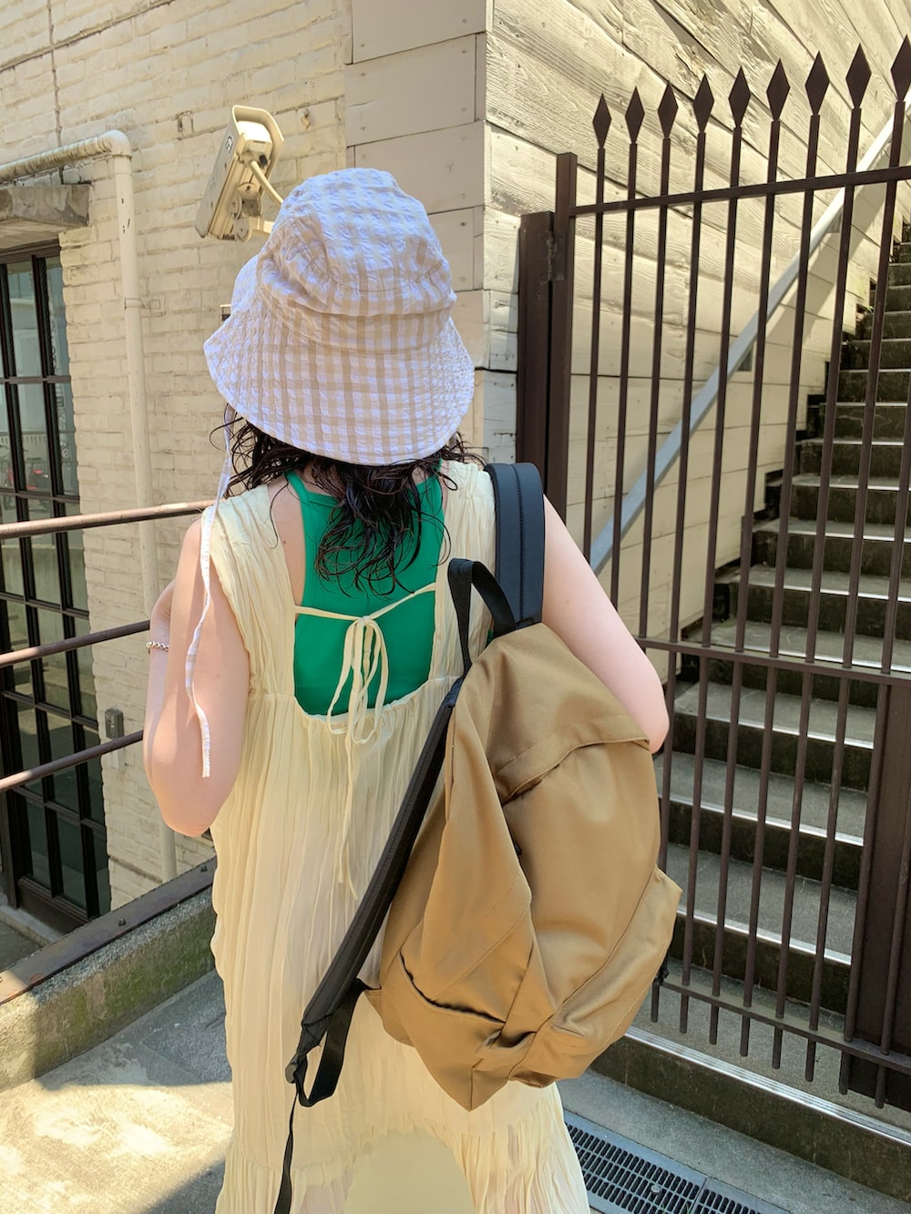 ホワイト系のワンピース、ベージュ系のバックパック/リュック、ホワイト系のサンダルを着用したレディースの夏コーディネートの2枚目の写真