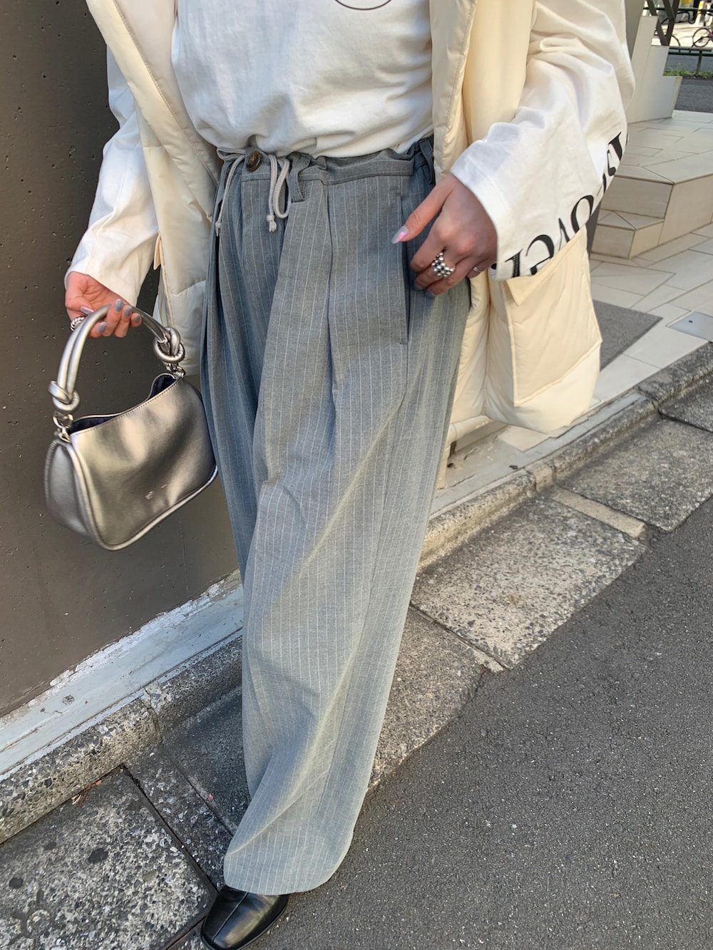 グレー系のスラックス、ホワイト系のベスト、ホワイト系のTシャツ/カットソーを着用したレディースの秋コーディネートの3枚目の写真