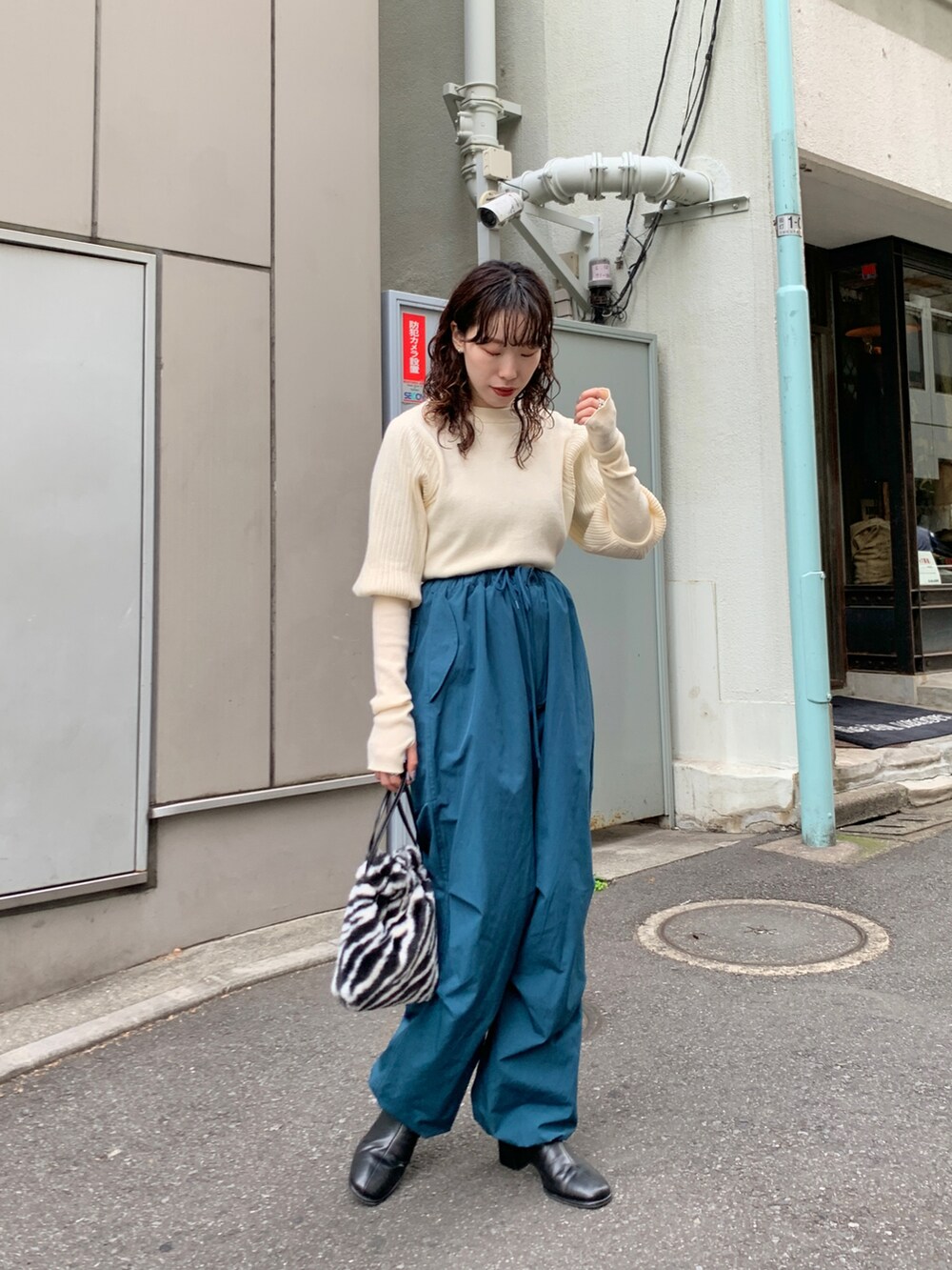 ブラック系のダウンジャケット/コート、ブルー系のカーゴパンツ、ホワイト系のカーディガン/ボレロを着用したレディースの秋コーディネートの5枚目の写真