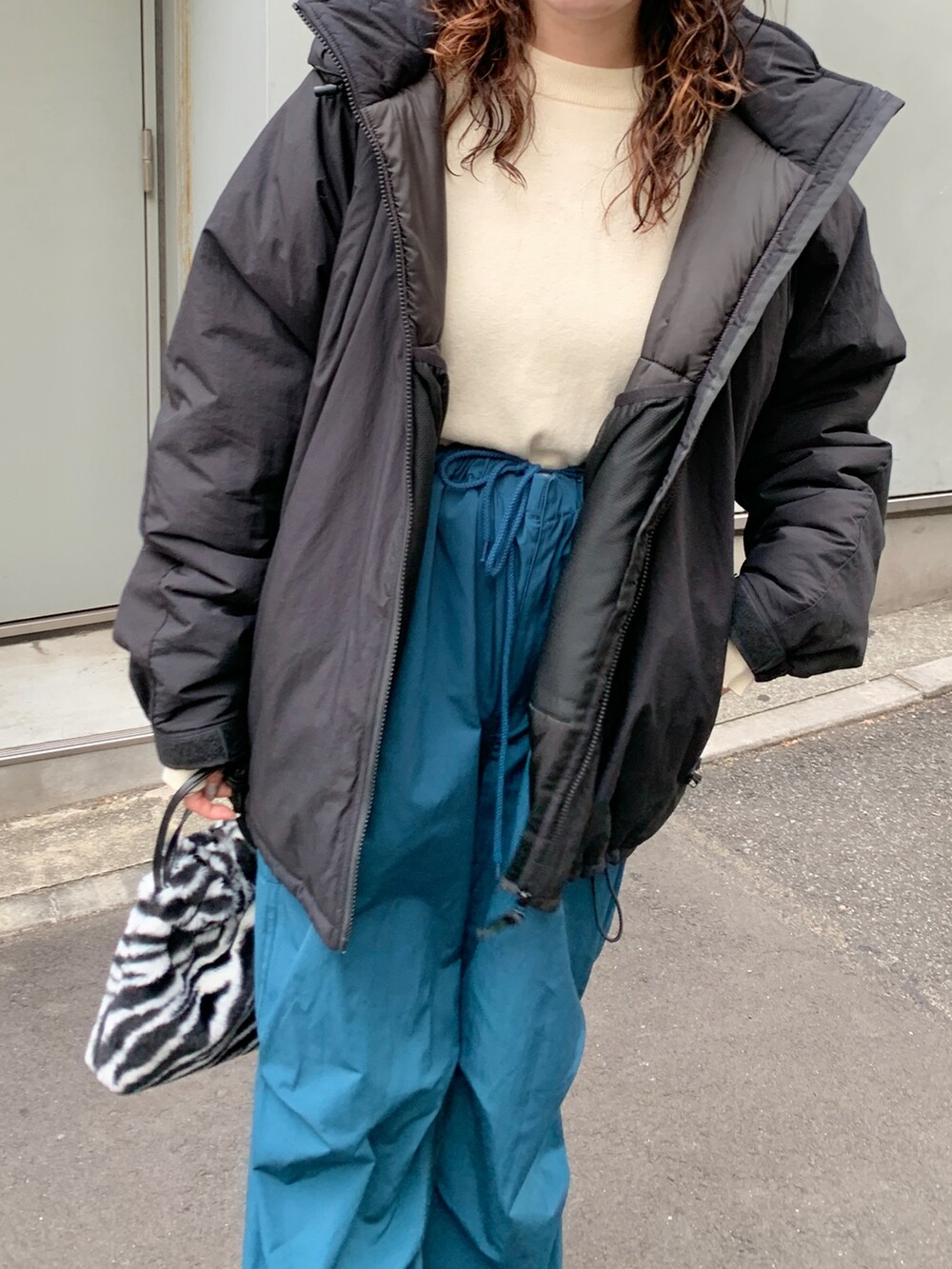 ブラック系のダウンジャケット/コート、ブルー系のカーゴパンツ、ホワイト系のカーディガン/ボレロを着用したレディースの秋コーディネートの2枚目の写真