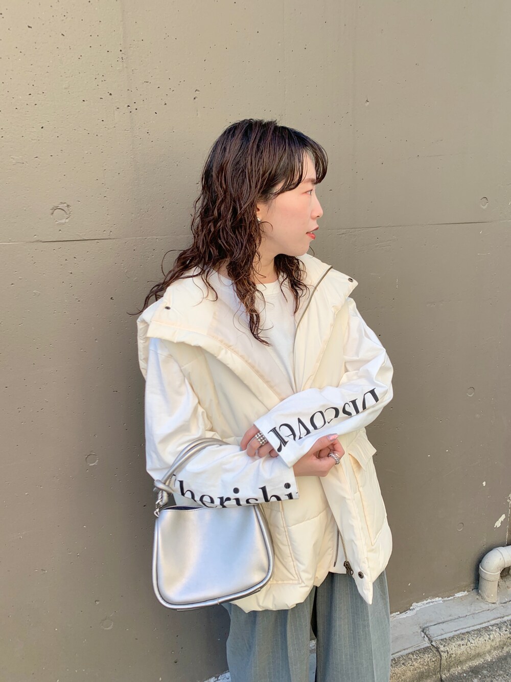 グレー系のスラックス、ホワイト系のベスト、ホワイト系のTシャツ/カットソーを着用したレディースの秋コーディネートの2枚目の写真