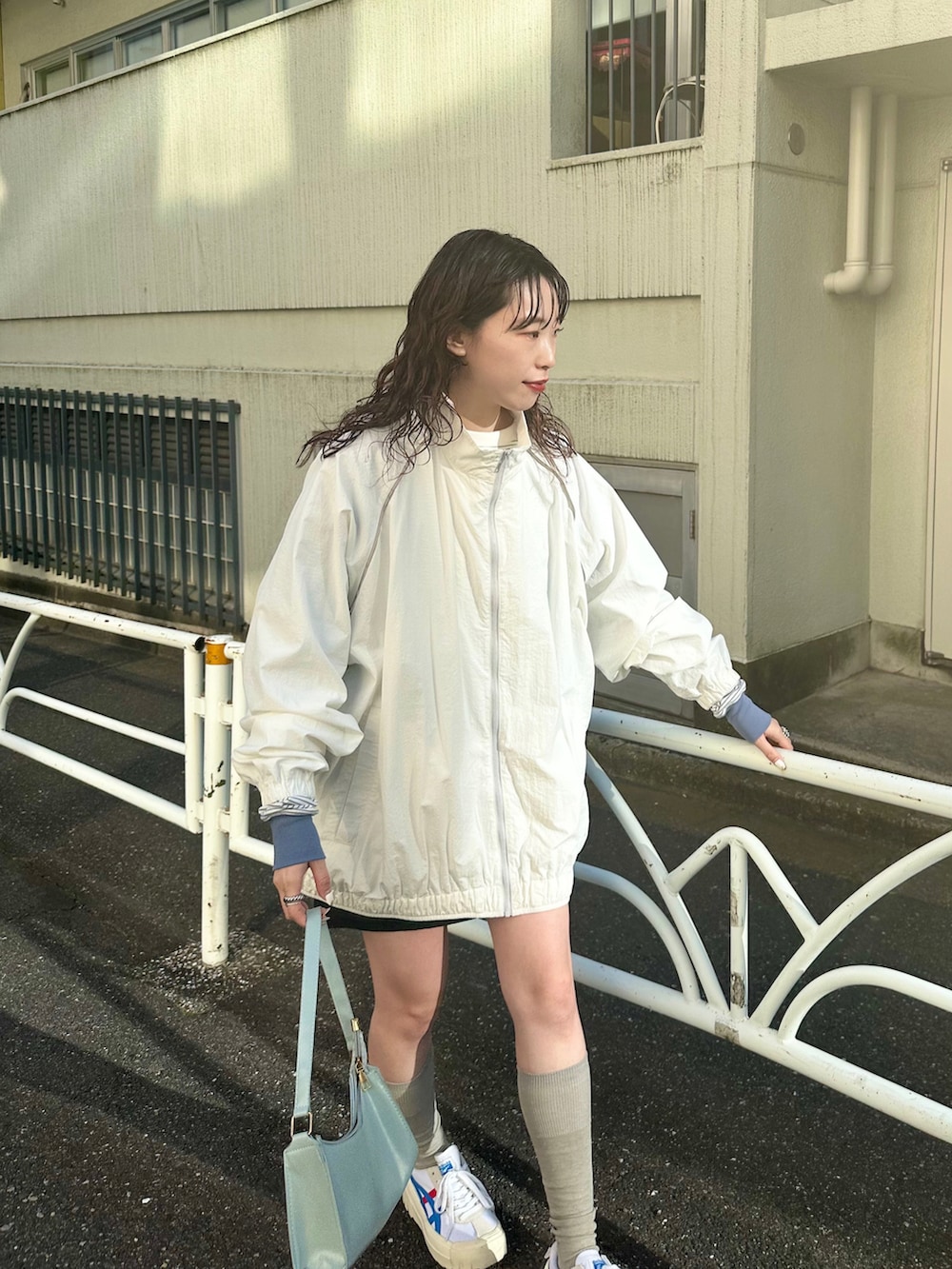 ブラック系のスカート、ホワイト系のナイロンジャケット、ホワイト系のTシャツ/カットソーを着用したレディースの春コーディネートの2枚目の写真