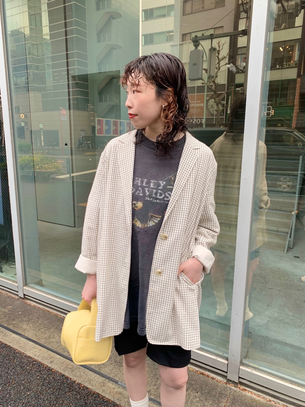 ホワイト系のテーラードジャケット、イエロー系のボストンバッグ、ブラック系のスリッポンを着用したレディースの春コーディネートの2枚目の写真