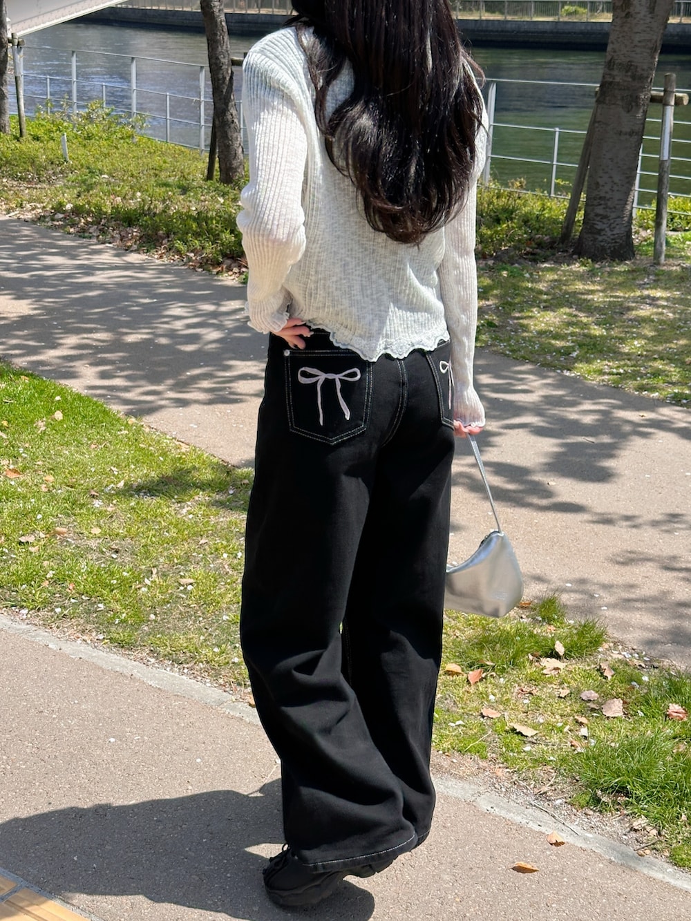 ブラック系のデニムパンツ、ホワイト系のカーディガン/ボレロ、ブラック系のTシャツ/カットソーを着用したレディースの春コーディネートの2枚目の写真