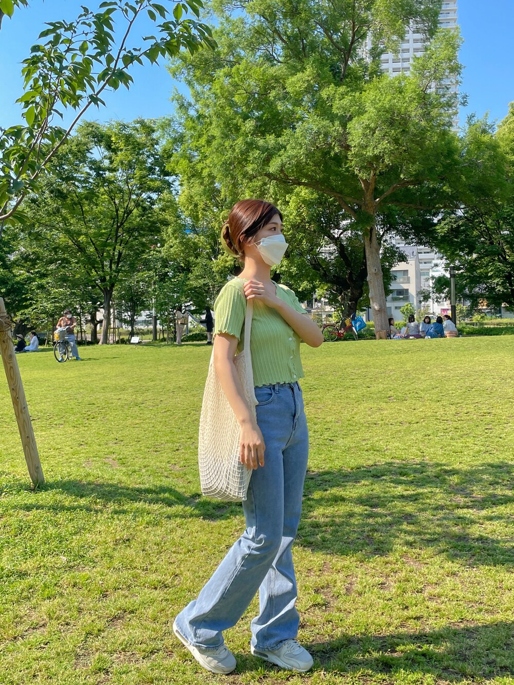 ホワイト系のショルダーバッグ、グリーン系のニット/セーター、ブルー系のデニムパンツを着用したレディースの夏コーディネートの2枚目の写真