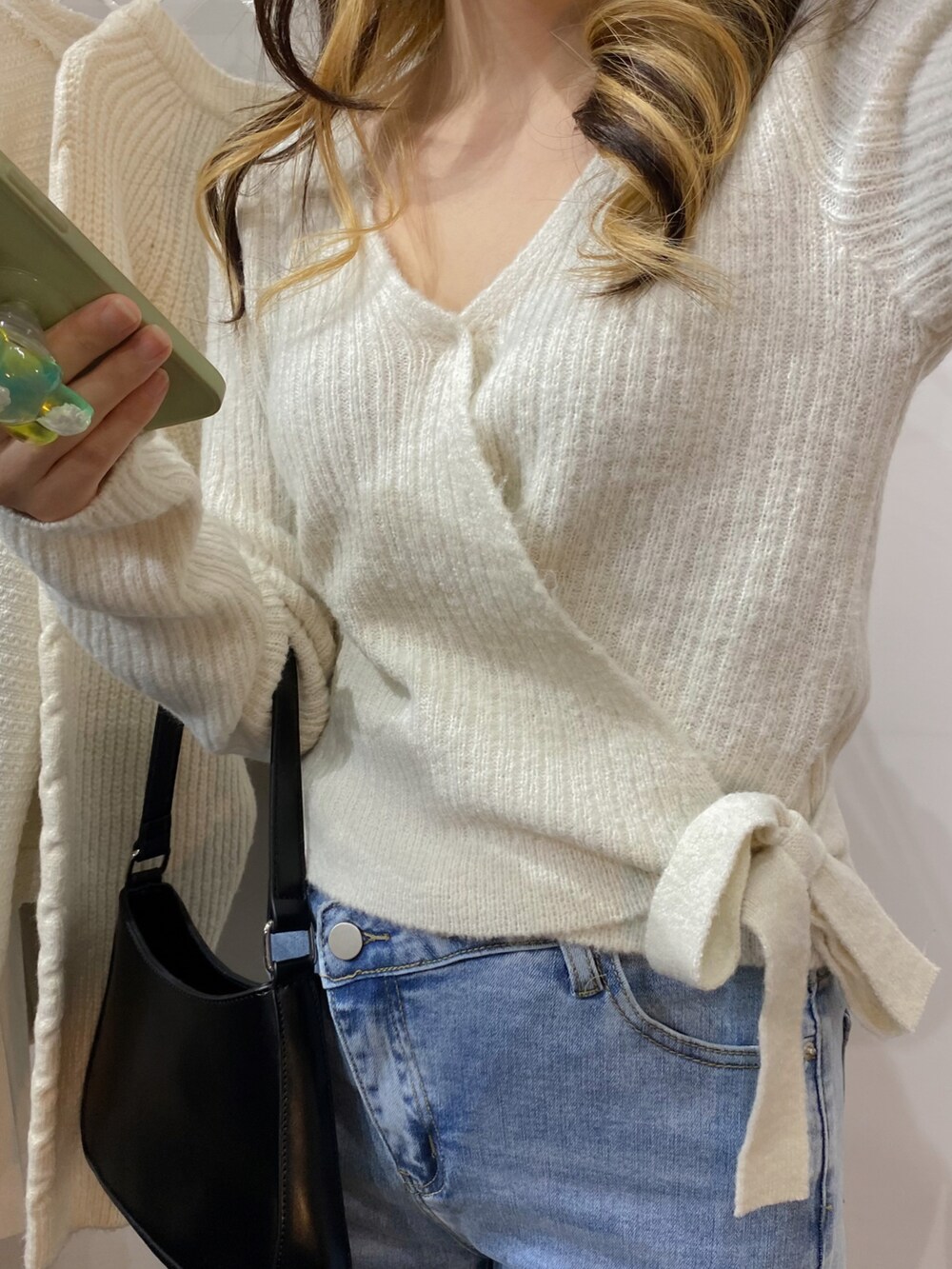 ホワイト系のカーディガン/ボレロ、ブラック系のショルダーバッグ、ブルー系のデニムパンツを着用したレディースの冬コーディネートの3枚目の写真