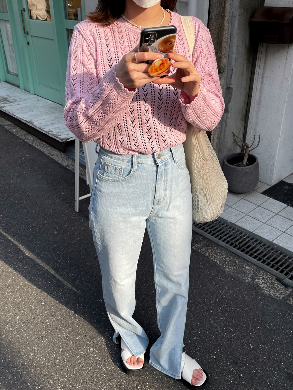 ピンク系のニット/セーター、ブルー系のデニムパンツ、ホワイト系のショルダーバッグを着用したレディースの春コーディネートの2枚目の写真