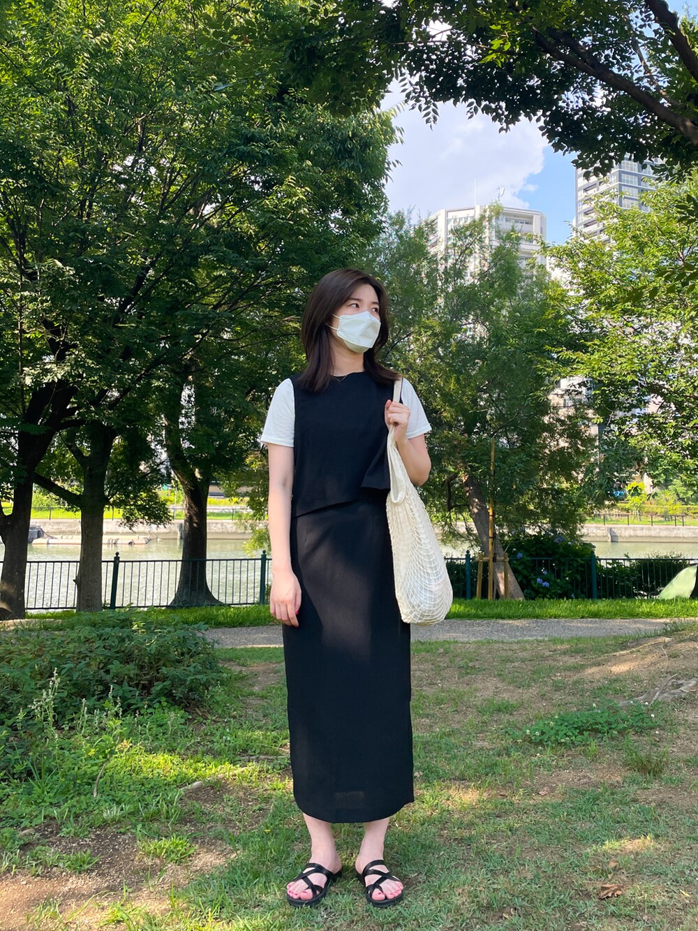 ホワイト系のショルダーバッグ、ホワイト系のTシャツ/カットソー、ブラック系のワンピースを着用したレディースの夏コーディネートの2枚目の写真