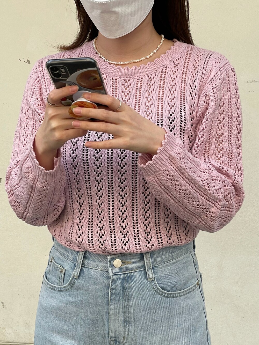 ピンク系のニット/セーター、ブルー系のデニムパンツ、ホワイト系のショルダーバッグを着用したレディースの春コーディネートの3枚目の写真
