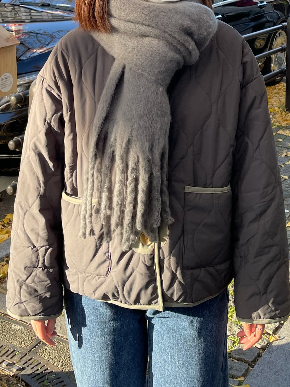 グレー系のテーラードジャケット、ブルー系のデニムパンツ、グレー系のマフラーを着用したレディースの冬コーディネートの3枚目の写真