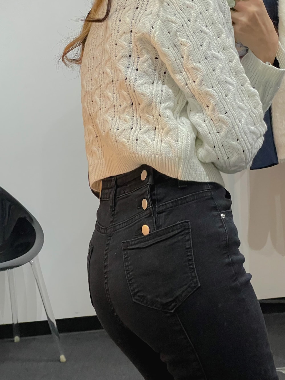 ホワイト系のニット/セーター、ブラック系のショルダーバッグ、ブラック系のデニムパンツを着用したレディースの冬コーディネートの4枚目の写真