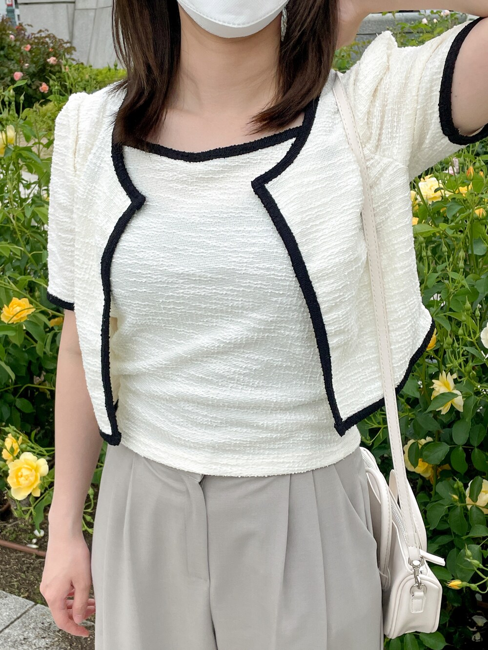 ベージュ系のスラックス、ホワイト系のカーディガン/ボレロ、ホワイト系のショルダーバッグを着用したレディースの春コーディネートの3枚目の写真