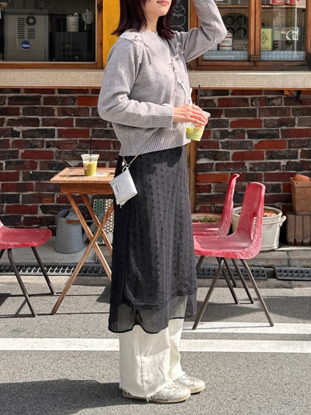 ブラック系のワンピース、グレー系のニット/セーターを着用したレディースの春コーディネートの2枚目の写真