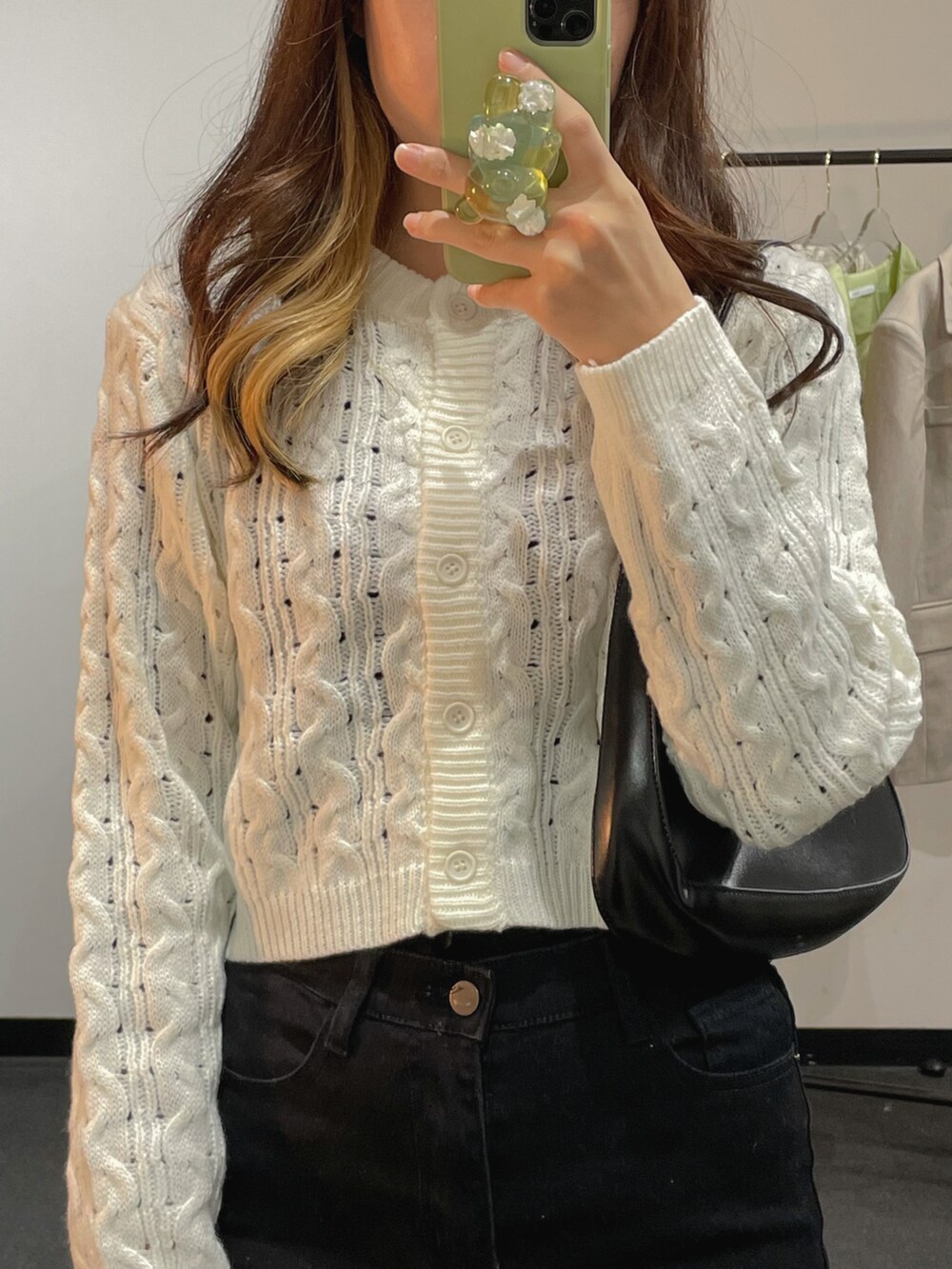 ホワイト系のニット/セーター、ブラック系のショルダーバッグ、ブラック系のデニムパンツを着用したレディースの冬コーディネートの3枚目の写真