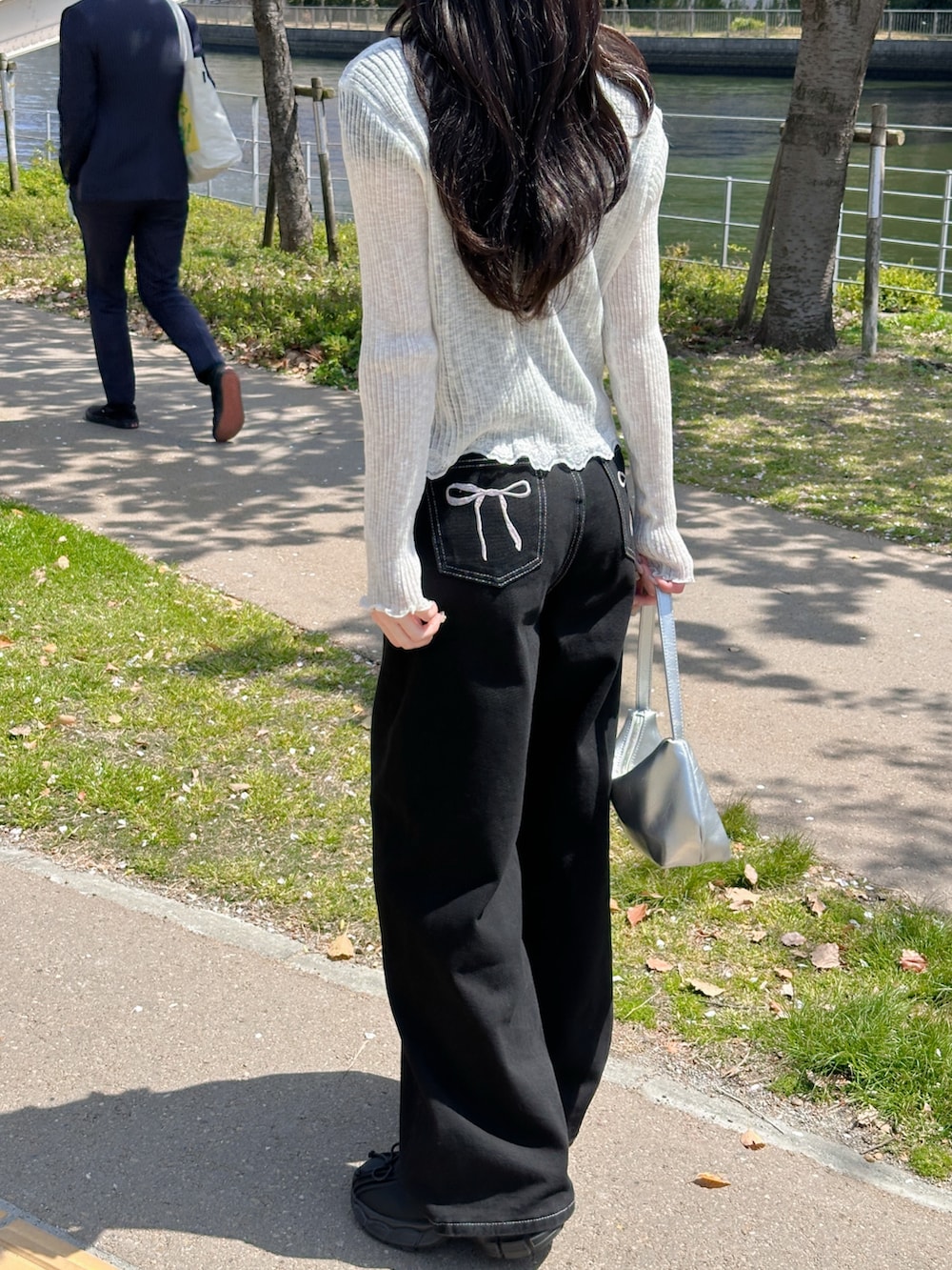 ブラック系のデニムパンツ、ホワイト系のカーディガン/ボレロ、ブラック系のTシャツ/カットソーを着用したレディースの春コーディネートの3枚目の写真