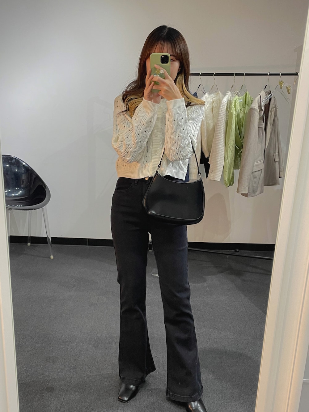 ホワイト系のニット/セーター、ブラック系のショルダーバッグ、ブラック系のデニムパンツを着用したレディースの冬コーディネートの2枚目の写真