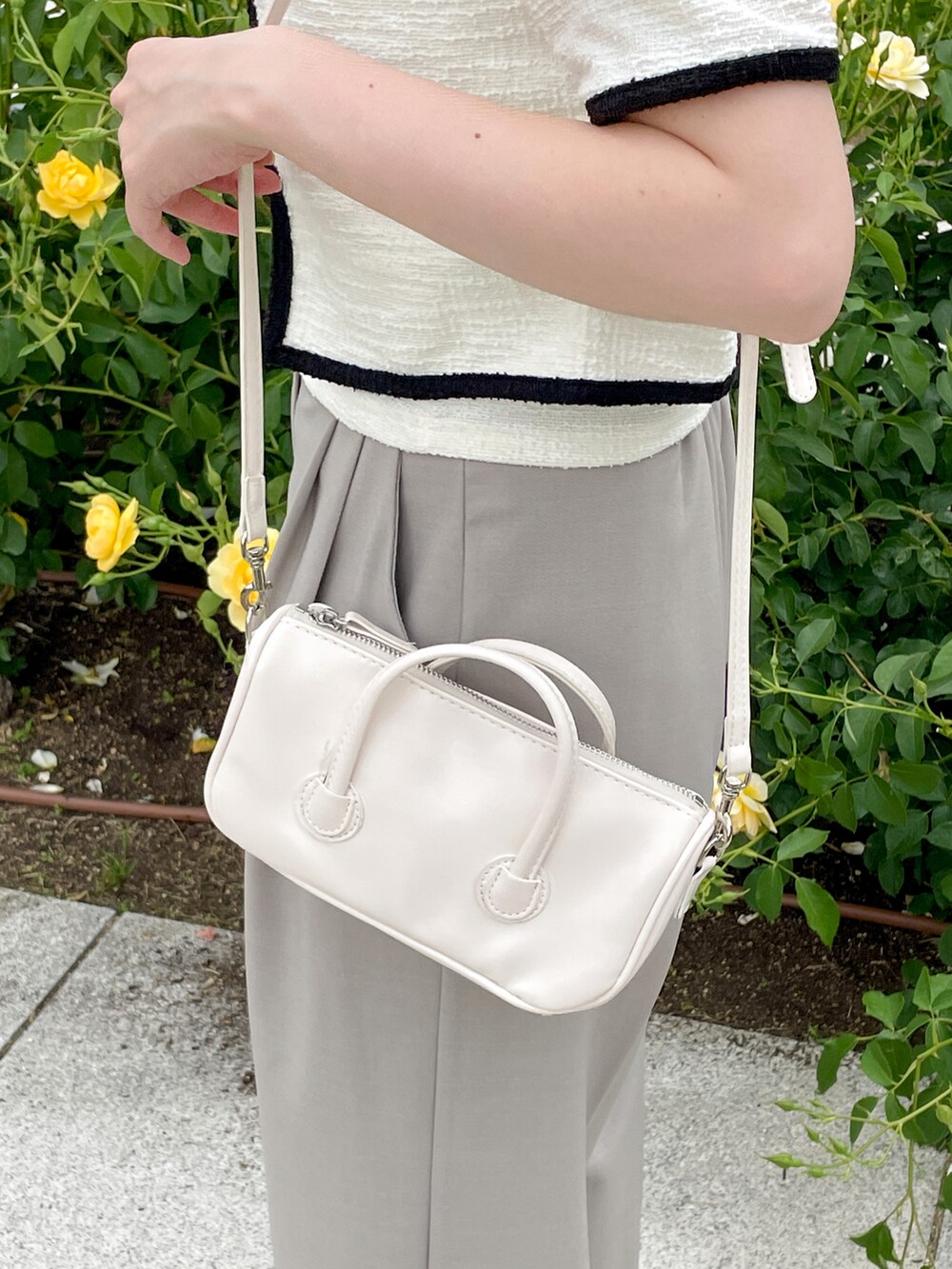 ベージュ系のスラックス、ホワイト系のカーディガン/ボレロ、ホワイト系のショルダーバッグを着用したレディースの春コーディネートの4枚目の写真